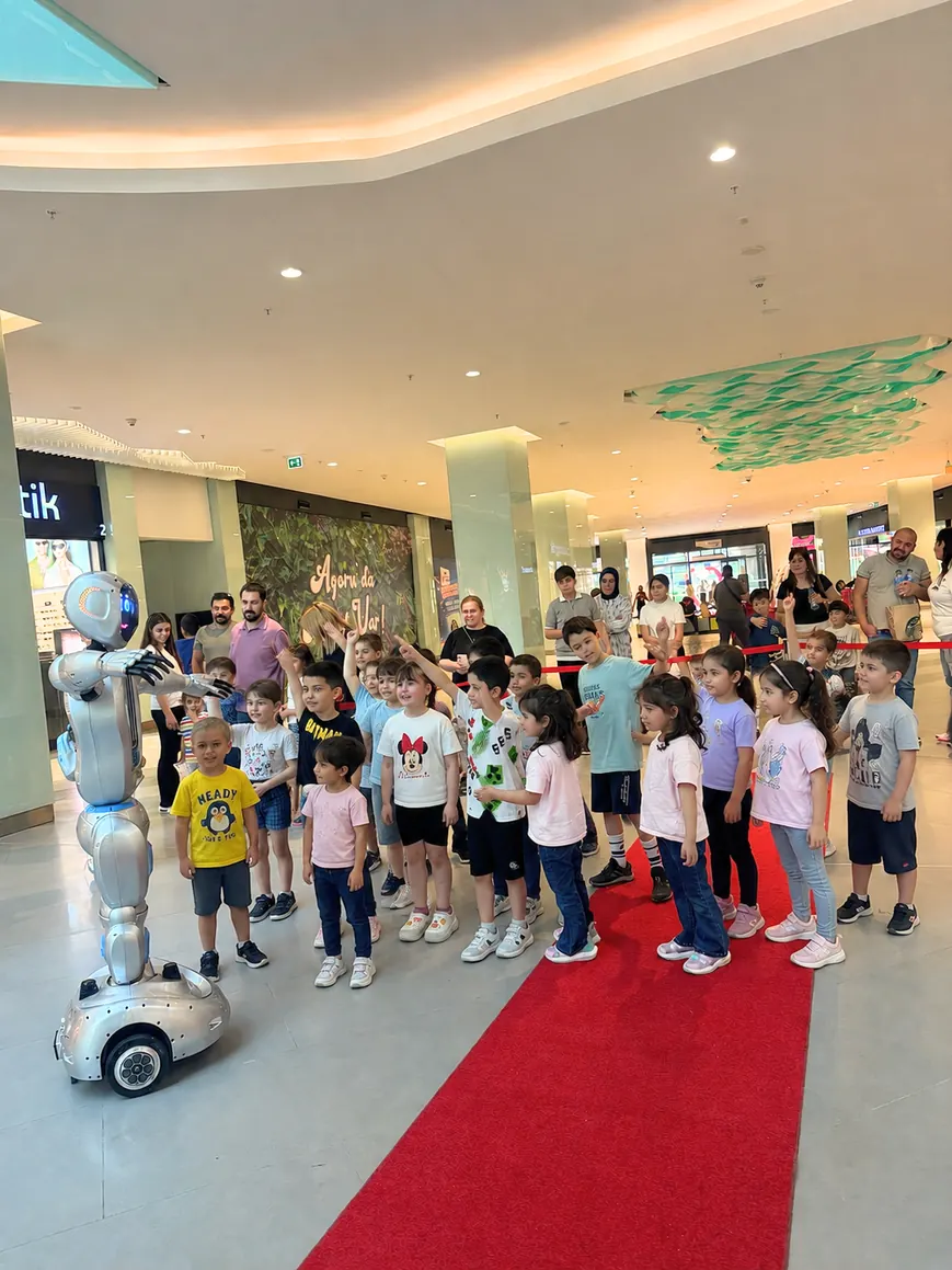 Çocuklar insansı robotla birlikte sıraya girmiş